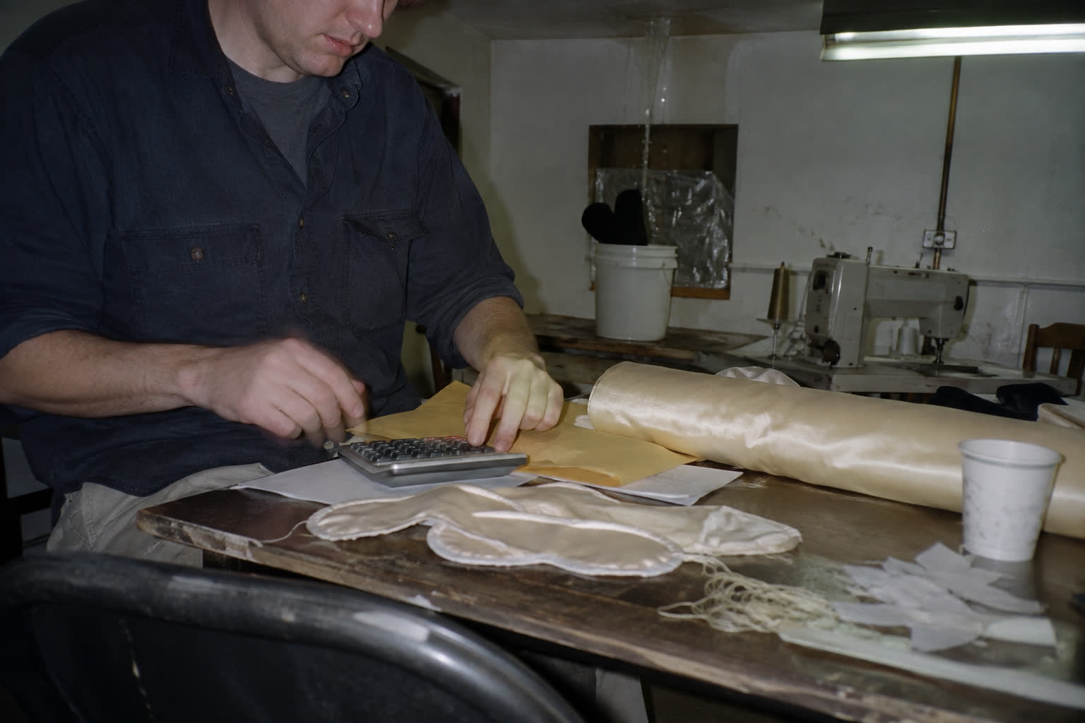 Peter reviewing costs beside an ivory roll of silk